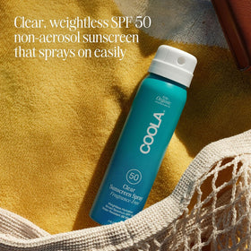 COOLA bottle held in hand showing 2 fl oz scale for travel-ready convenience