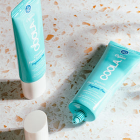 COOLA sunscreen inside beach bag conveying travel-ready protection benefit