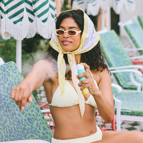 COOLA bottle in hand illustrating 2 fl oz travel size convenience benefit