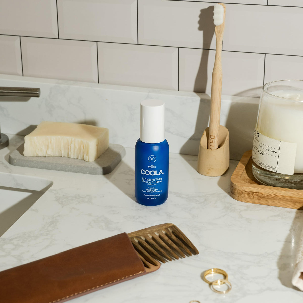 COOLA bottle next to coin showing compact travel-friendly benefit