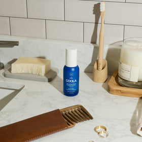 COOLA bottle next to coin showing compact travel-friendly benefit