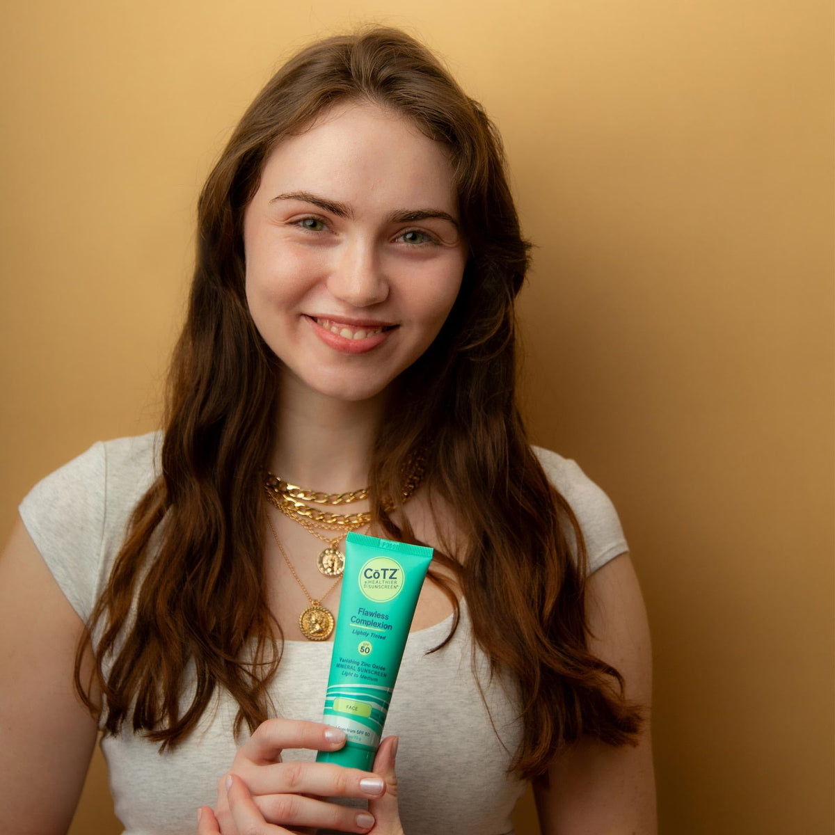 Model applying CoTZ to face illustrating smooth, non-greasy feel