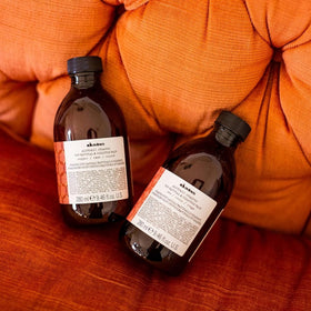 Product size comparison with hand showing Davines 9.47 fl oz bottle for at-home use