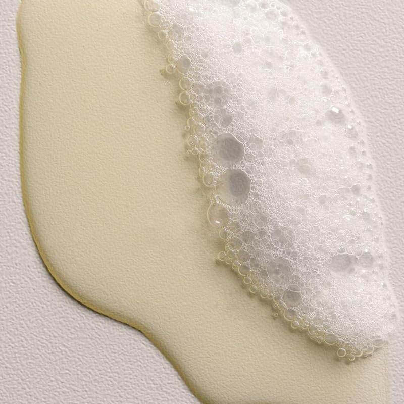 Davines DEDE applied to wet hair in hand showing gentle lathering benefit