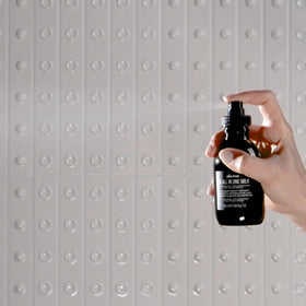Davines OI size comparison in hand to show full-size bottles and travel milk portability