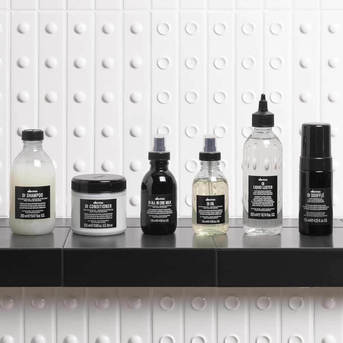 Davines OI Soufflé beside common travel items showing portable 1.69 fl oz convenience