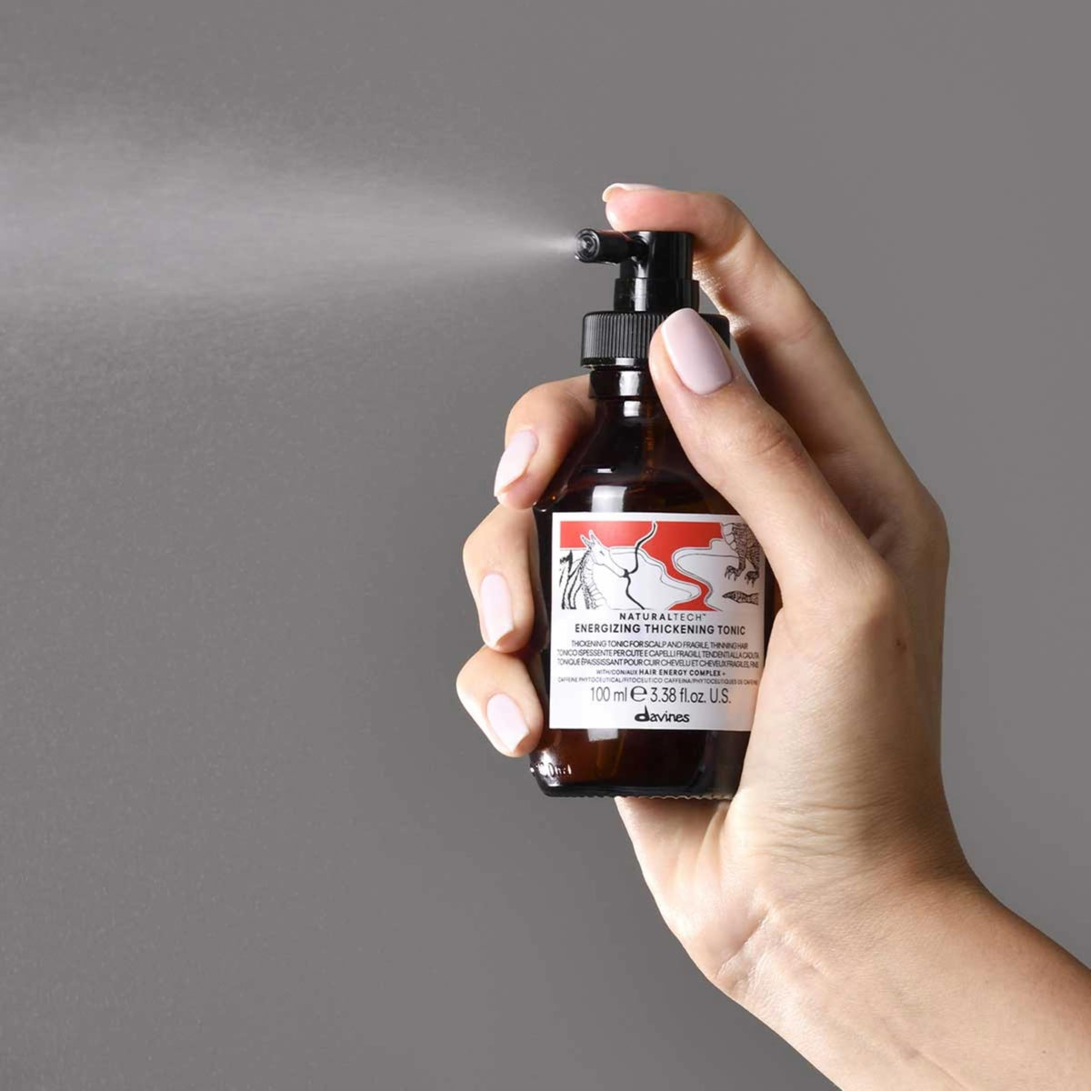 Davines travel-size bottle in hand for portability benefit