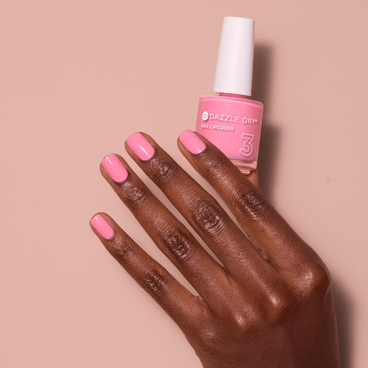 Dazzle Dry bottle held in a hand to show size and travel-friendly benefit