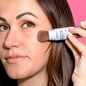 DERMA E compact size in purse illustrating travel-ready SPF and on-the-go convenience