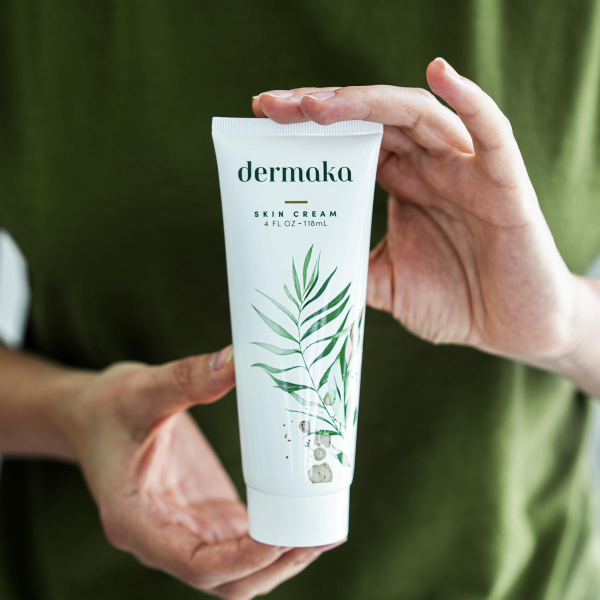 Dermaka size scale next to phone illustrating travel-friendly 4 oz jar