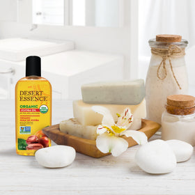 Jojoba seeds and Desert Essence bottle together to show plant origin and cold-pressed source