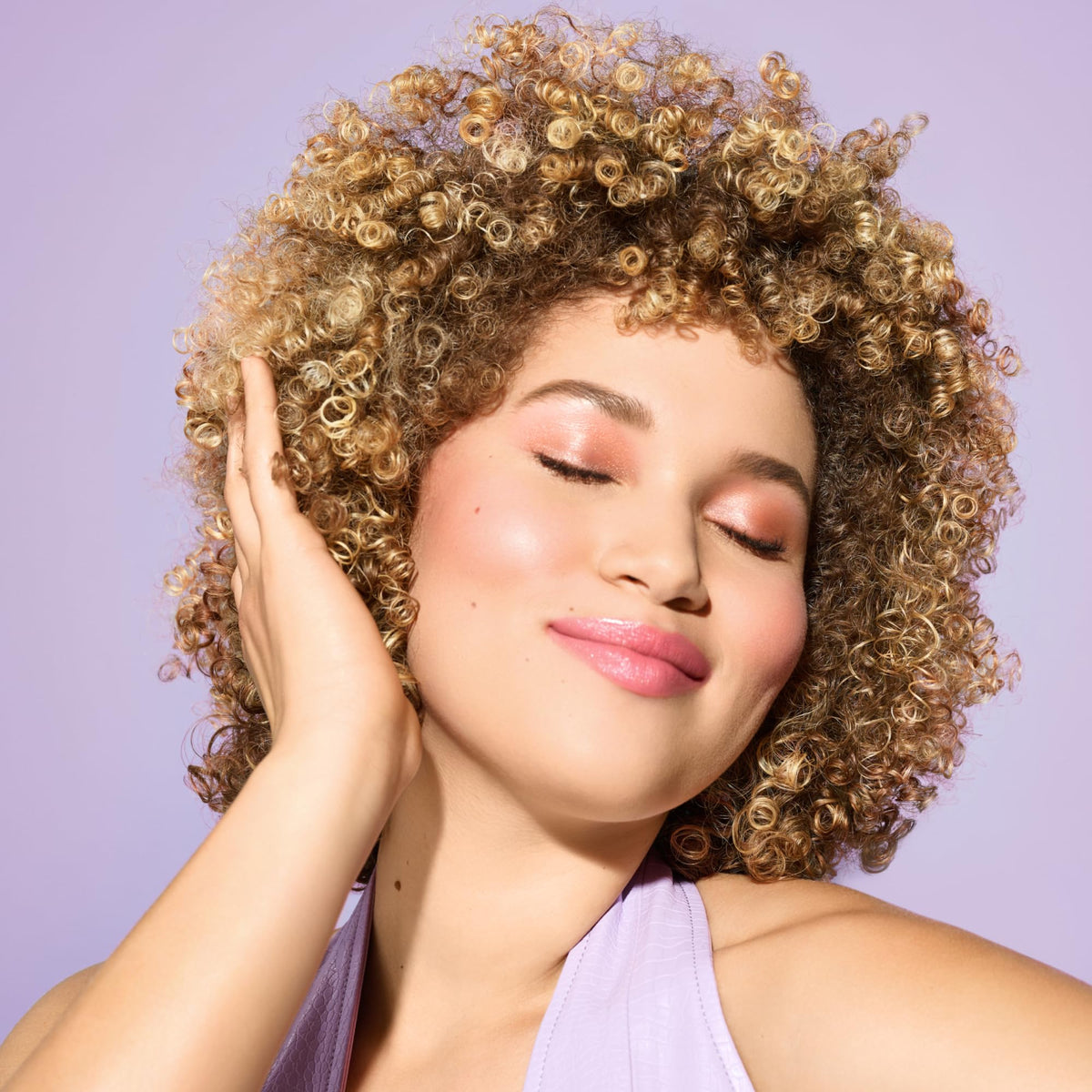 Hands applying DevaCurl cleanser into wet curls showing low-lather coverage