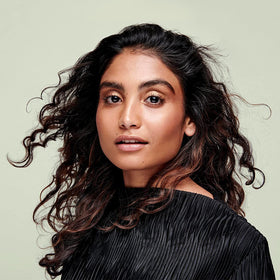DevaCurl product being applied to curly hair demonstrating detangling benefit