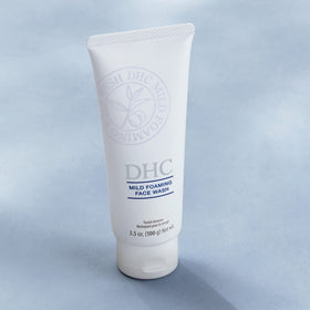 DHC tube beside hand for scale emphasizing compact travel-friendly size