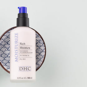 DHC Rich Moisture next to a hand for scale indicating travel-friendly 3.3 oz