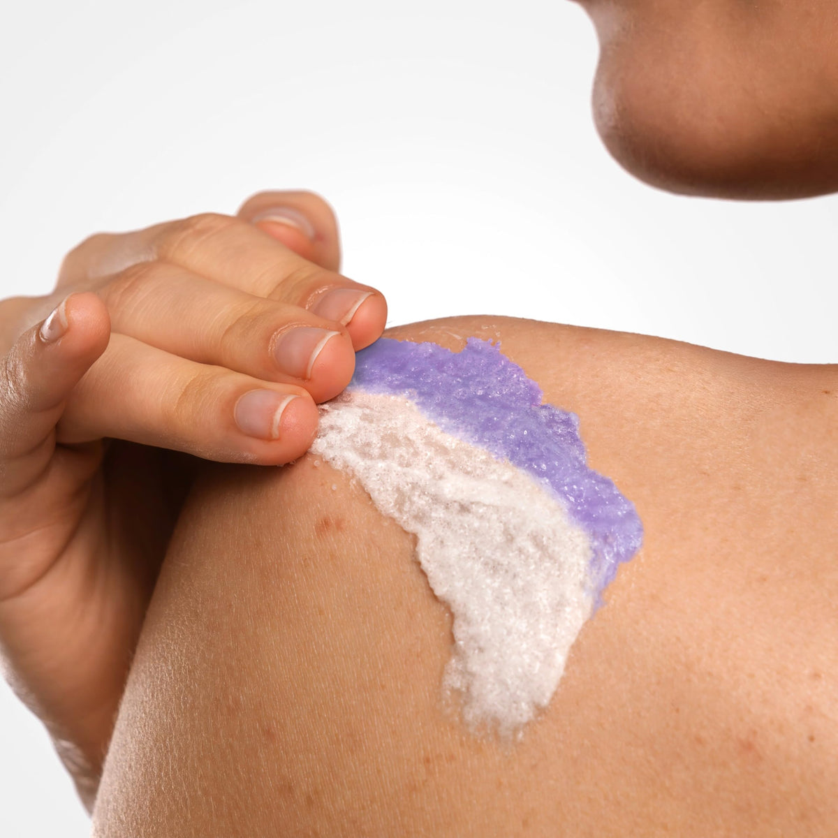 Hand applying Dove scrub to wet skin demonstrating smoothing exfoliation