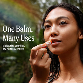 Dr. Bronner's lip balm in hand demonstrating size and portable benefit for on-the-go use