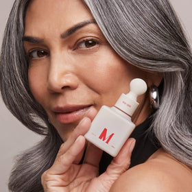 Dr. Diamond's Metacine bottle beside makeup highlighting layering under cosmetics for even finish