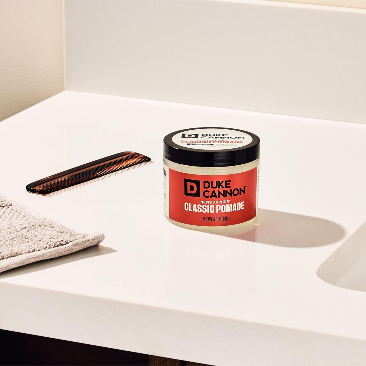 Hand holding Duke Cannon 4.6 oz jar to show travel-friendly size and convenience