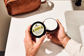 Duke Cannon 5 oz tin next to a smartphone to show compact size