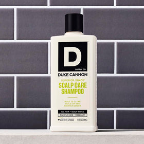 Hand holding 14 oz bottle showing Duke Cannon size and portability
