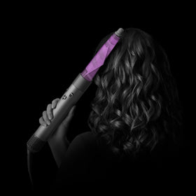Dyson conical Airwrap next to hand to show size and effortless handling benefit