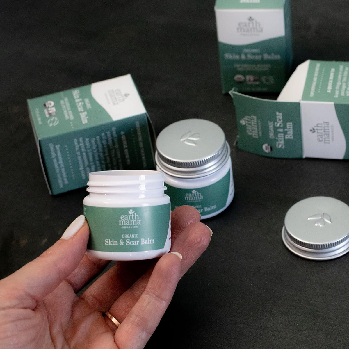 Earth Mama pocket tin in a bag representing travel-ready scar and skin care on the go