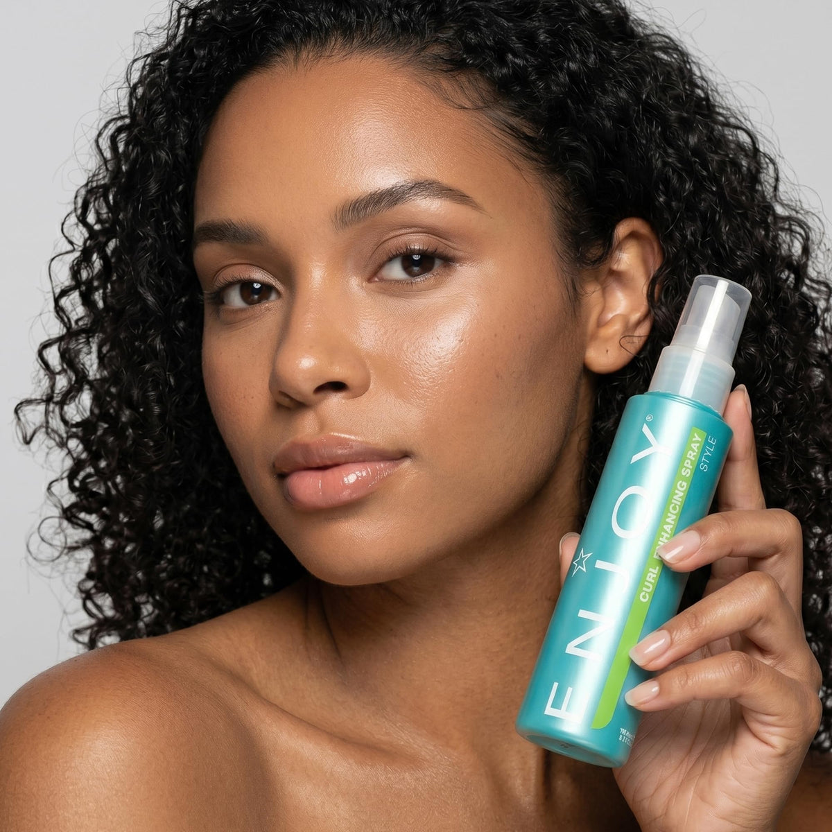 Enjoy bottle styled on bathroom shelf suggesting everyday use and salon-finish results