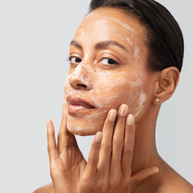 Estée Lauder product in use cleansing face, conveys a soothing, soft-skin benefit