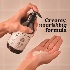 Fable & Mane coconut halves near bottle, illustrating smoothing coconut oil benefit