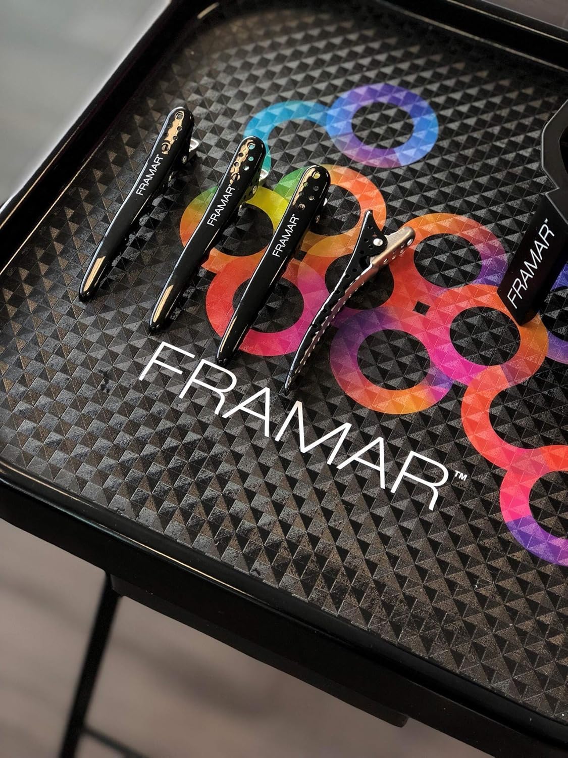FRAMAR clip beside a hand to show compact size and control