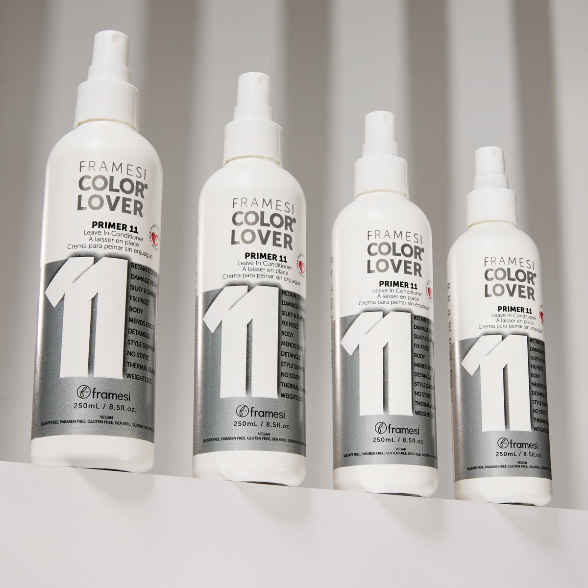 Hand spraying Framesi primer on damp hair demonstrating detangling and heat protection