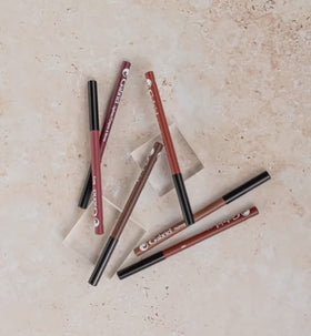 Gabriel Cosmetics lipliner next to coin to show compact .04 oz size for travel convenience
