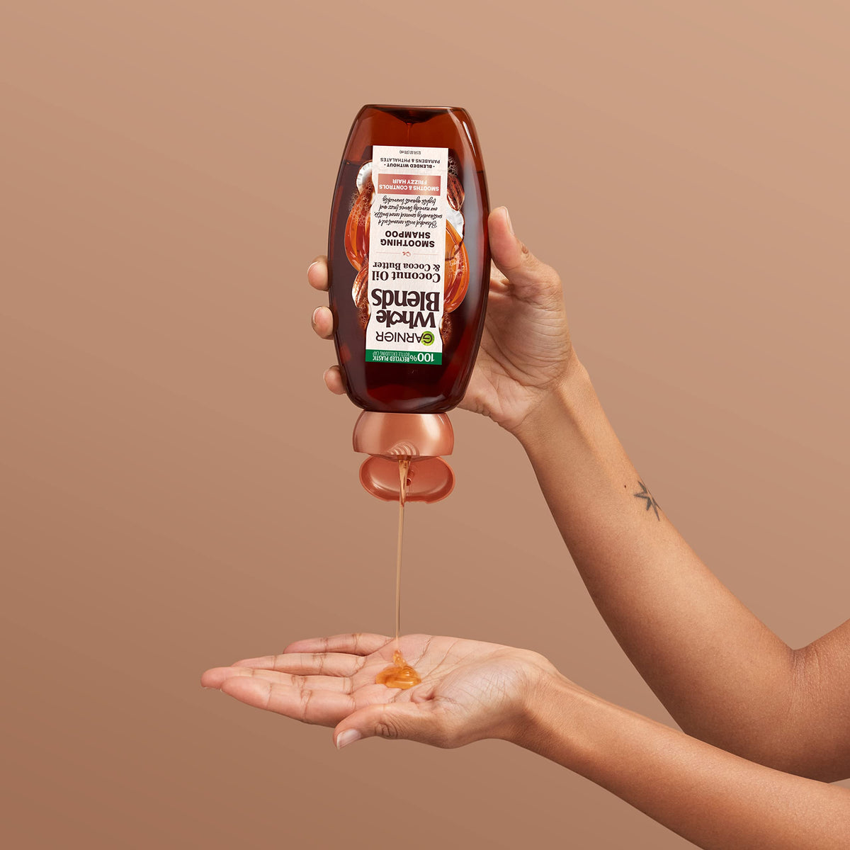 Garnier Whole Blends bottle next to hand illustrating 22 fl oz size
