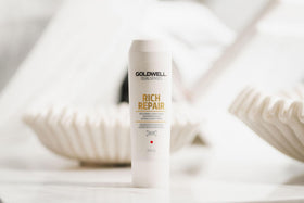 Goldwell bottle next to hand to show 1L scale for long-lasting supply
