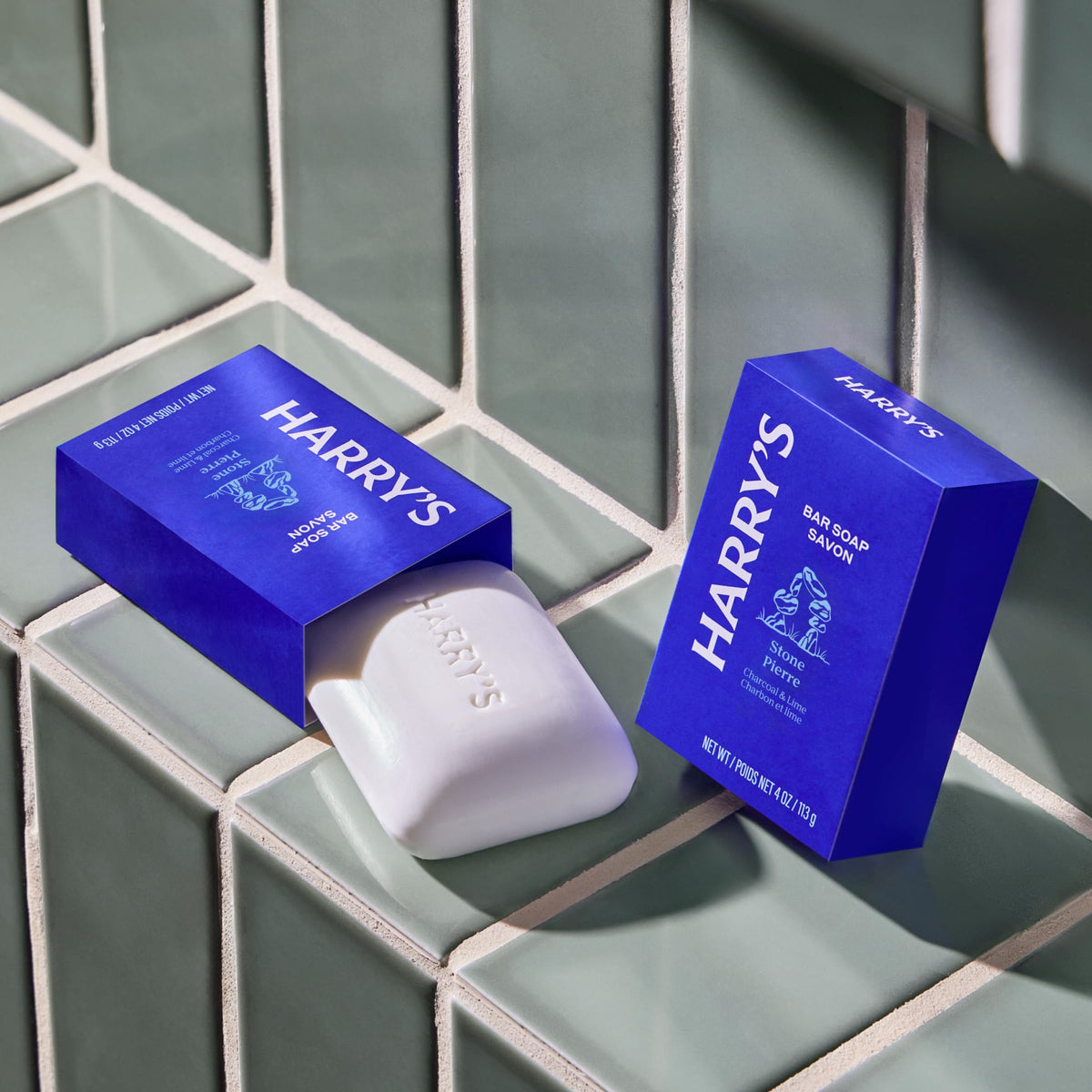 Hand holding Harry's Stone bar showing compact 4 oz travel-friendly size