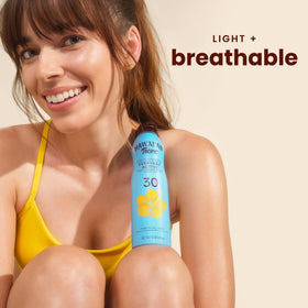 Hawaiian Tropic clear spray action on skin showing non‑greasy finish