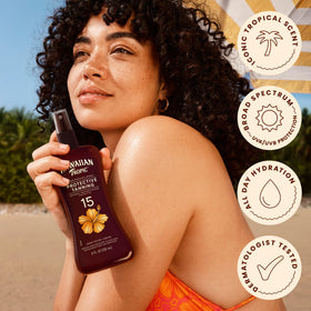 Hawaiian Tropic spray being applied at the beach for water-resistant coverage