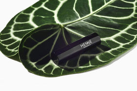 Henné Organics lip balm held in hand to show scale and pocketable convenience