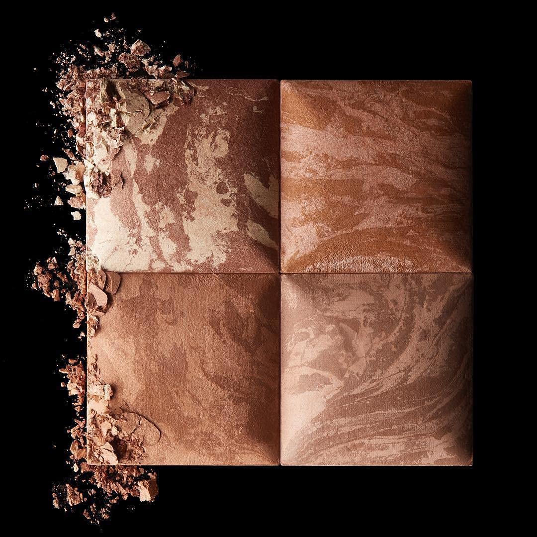 HOURGLASS bronzer in a makeup bag beside a mirror illustrating travel-ready application benefit