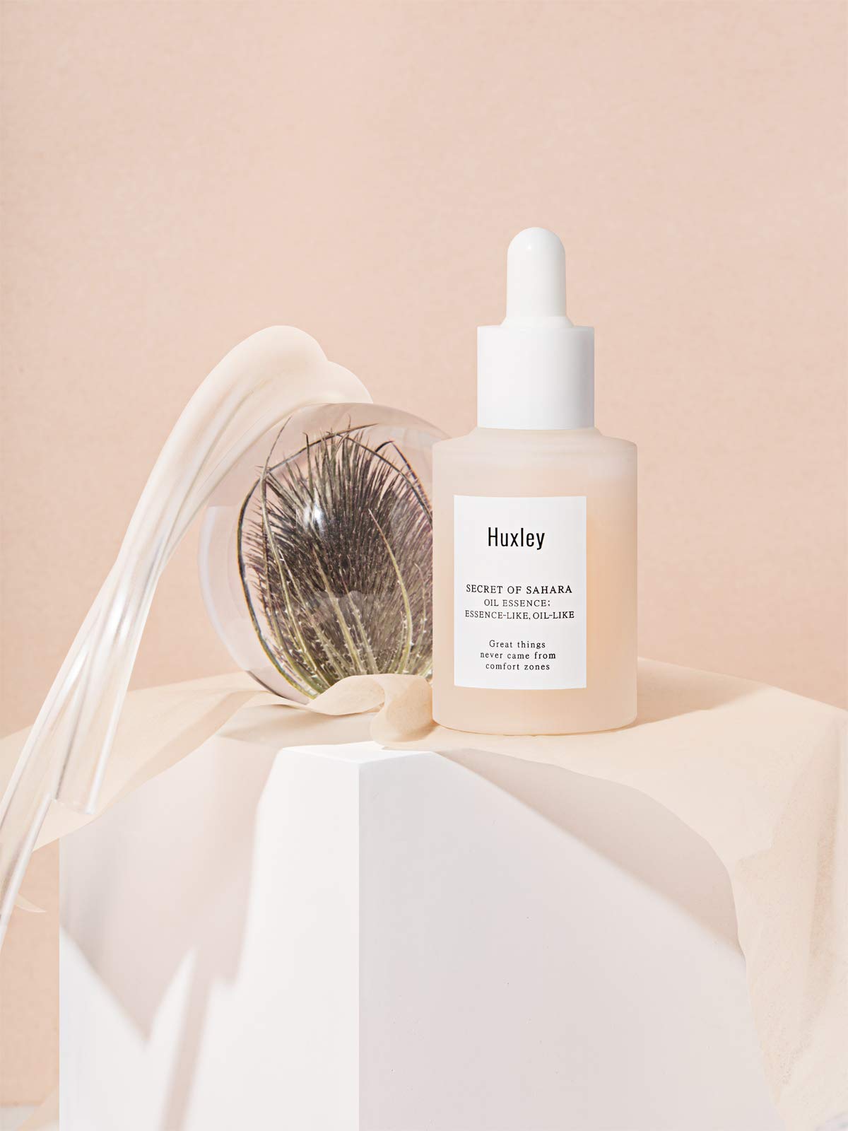 Hand applying Huxley oil essence to face for lightweight hydration and smooth finish