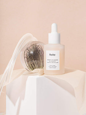 Hand applying Huxley oil essence to face for lightweight hydration and smooth finish