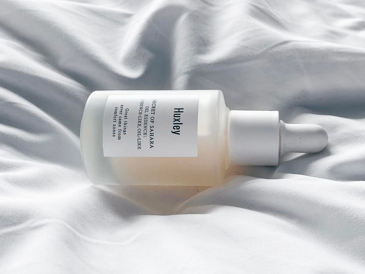 Huxley oil essence on bathroom shelf in routine setting, suggests easy daily layering