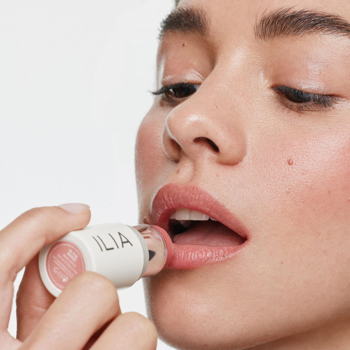 ILIA applied on cheek showing natural golden peach pearl glow and fresh radiance