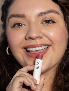 ILIA tube beside coin to show compact size and travel-friendly benefit