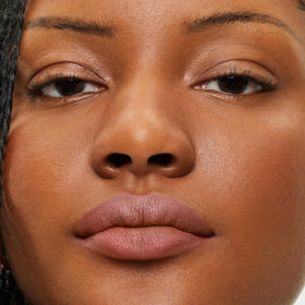 ILIA lip sketch on model neutral beige shade offering natural flattering look
