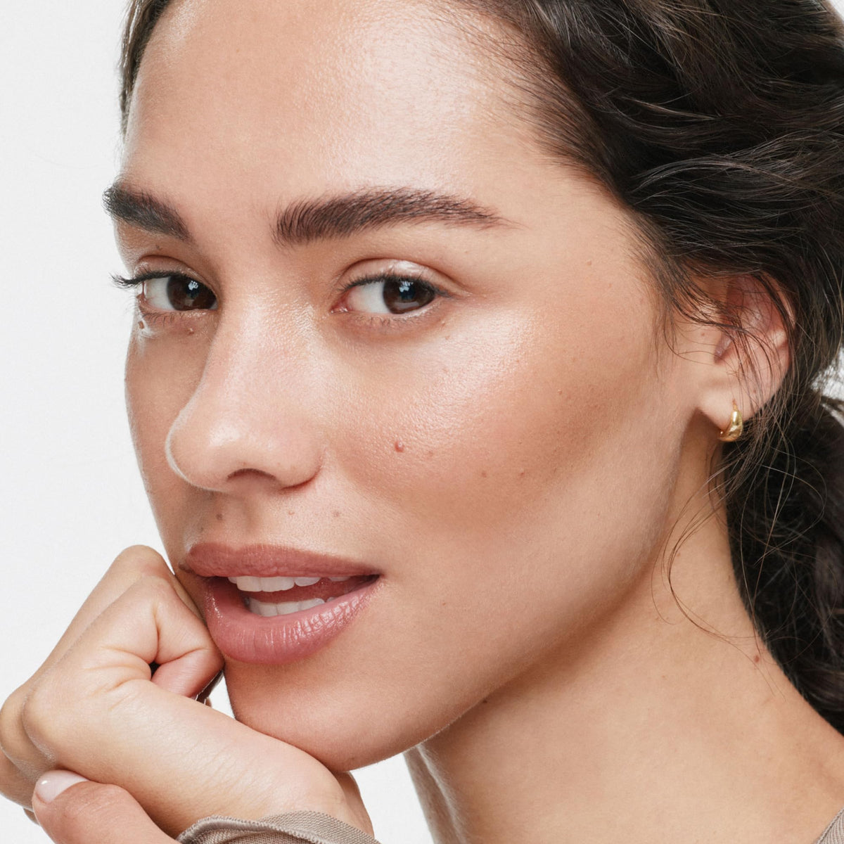 ILIA multi‑stick applied on cheek showing natural luminous finish benefit