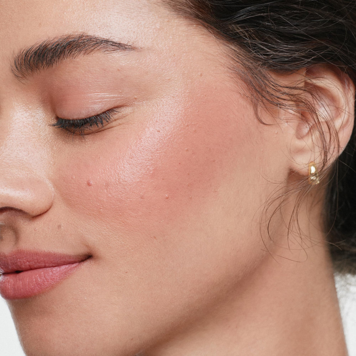 ILIA multi‑stick applied on cheek closeup illustrating natural buildable color and healthy glow