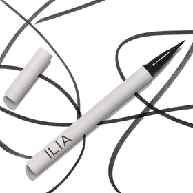 ILIA liner beside small everyday items for scale showing compact travel-friendly size