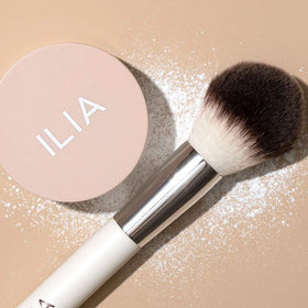 ILIA powder being picked up with a fluffy brush to demonstrate effortless application and even coverage